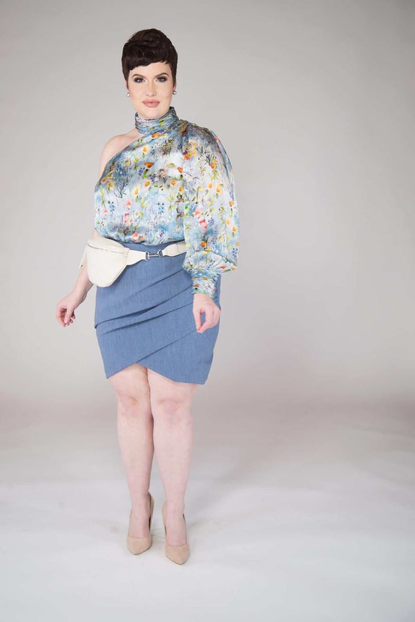 short haired model wears a Campanula Blue colored Tulip Mini Skirt with End on End Texture with a True Waisted with Side Ruching and Crossed Front Hem Details include: Full Garment Lining and Center Back Invisible Back Zipper. Fabric is Viscose/Poly/Spandex  garment is MADE IN NEW YORK CITY BY Mayes NYC