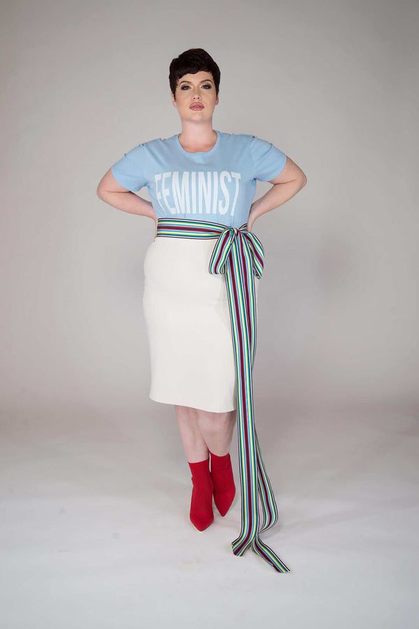 short haired model wearing an ecrue colored pull on hight waisted, form fitting skirt. Finished with 2 inch elastic waist and center back kick pleat Material is a Viscose/Poly/Spandex  garment is MADE IN NEW YORK CITY BY Mayes NYC
